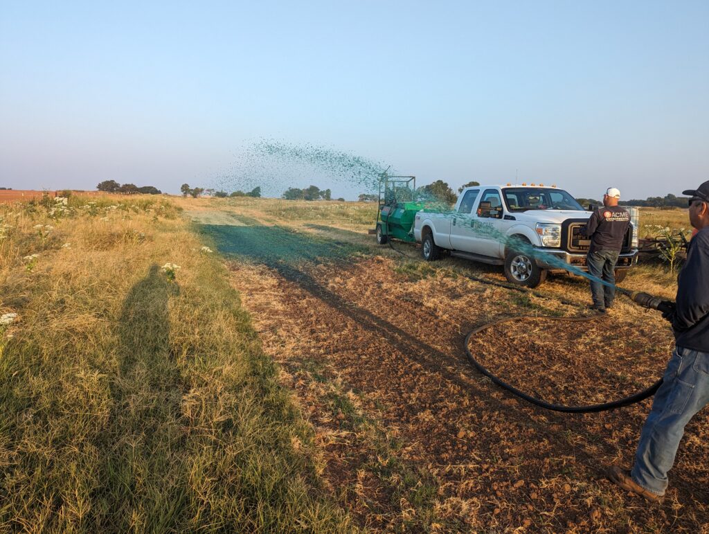 A picture of ACME employees hydroseeding soil to promote vegetation growth after the soil had been remediated