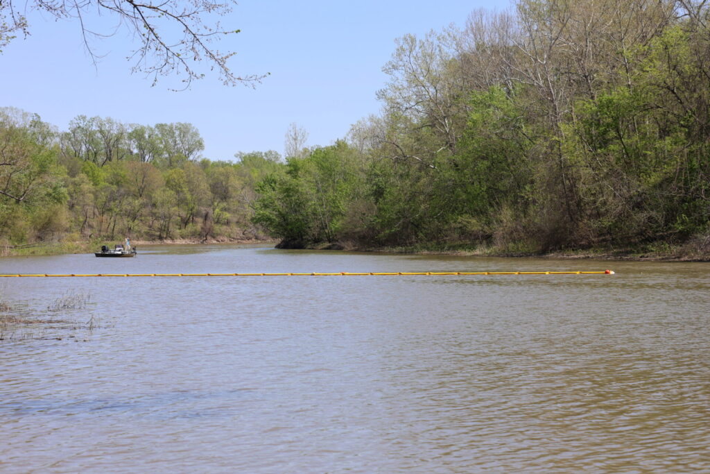 Containment boom being pulled across river
