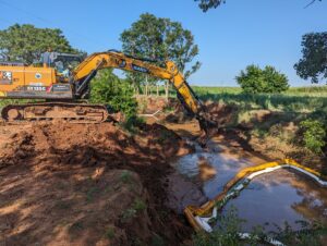 An excavator removing oily sludge from a creek bank to be hauled off and disposed of