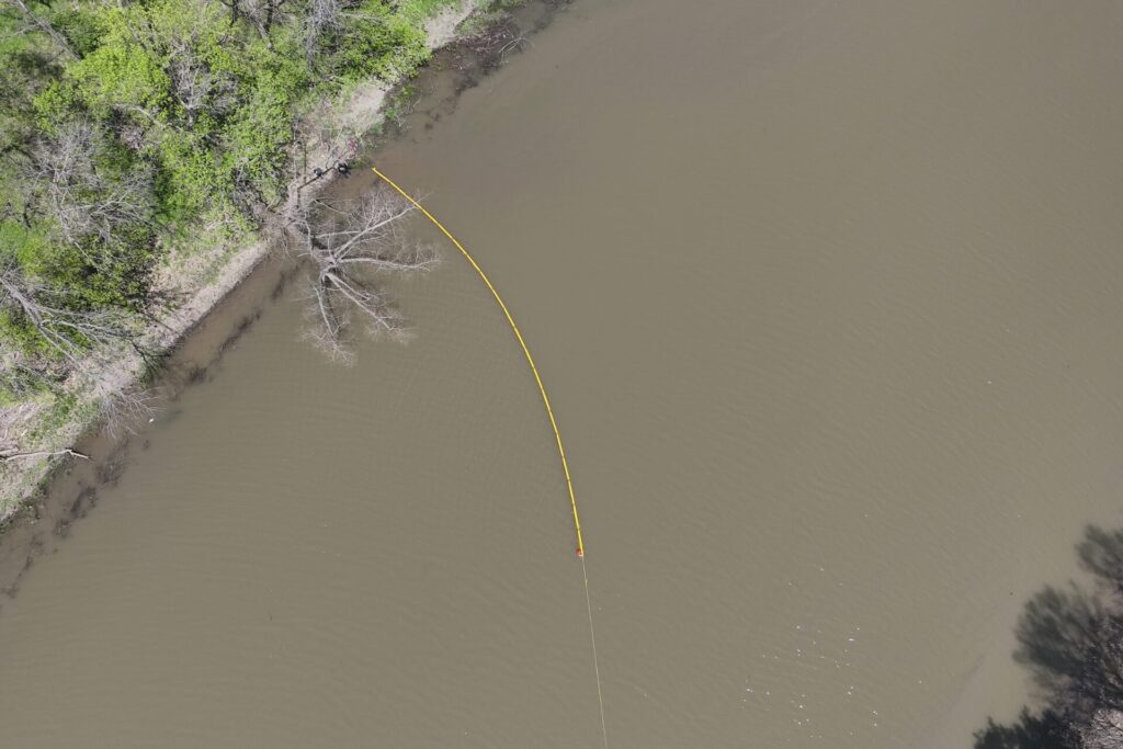 Containment boom being pulled across river