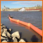 ACME employees deploying inflatable containment boom in large river