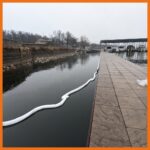 Absorbent boom deployed around a boat dock to keep oil contained