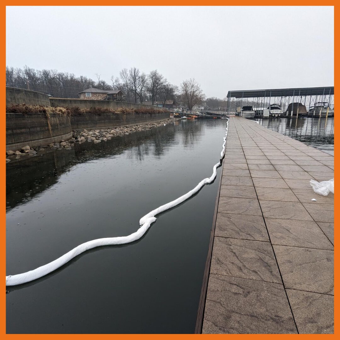 Absorbent boom deployed around a boat dock to keep oil contained