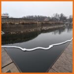 Absorbent boom deployed around a boat dock