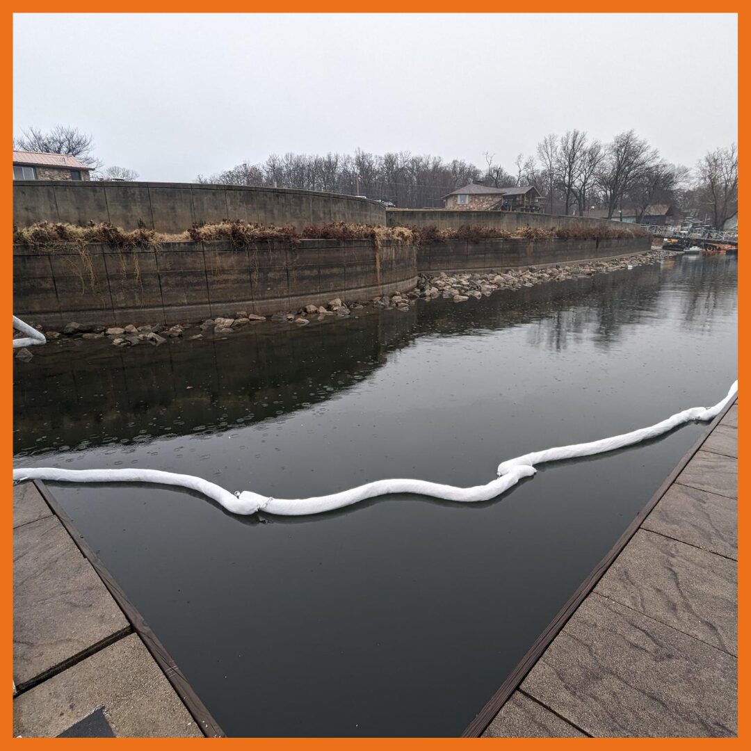 Absorbent boom deployed around a boat dock