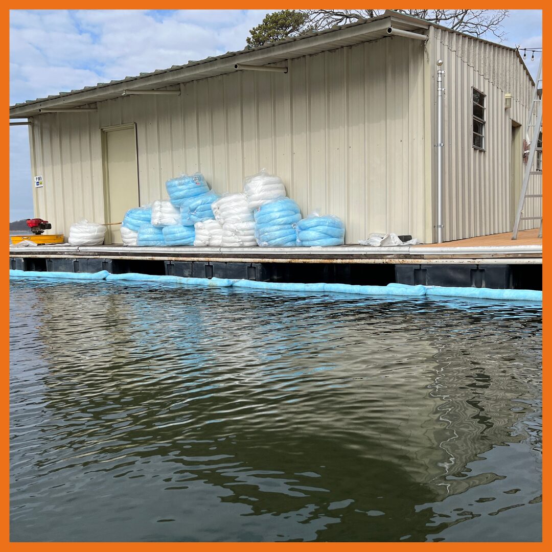 Absorbent boom deployed around a boat dock to contain spilled oil